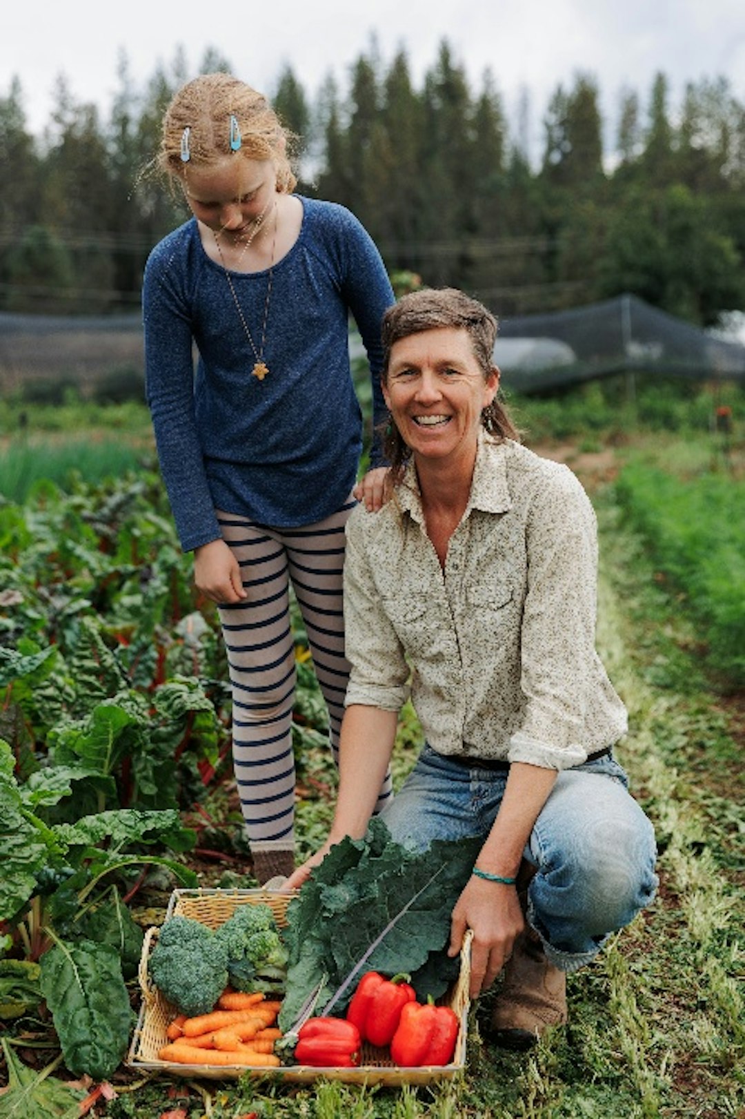 Diane and Sage displaying vegetables at the farm