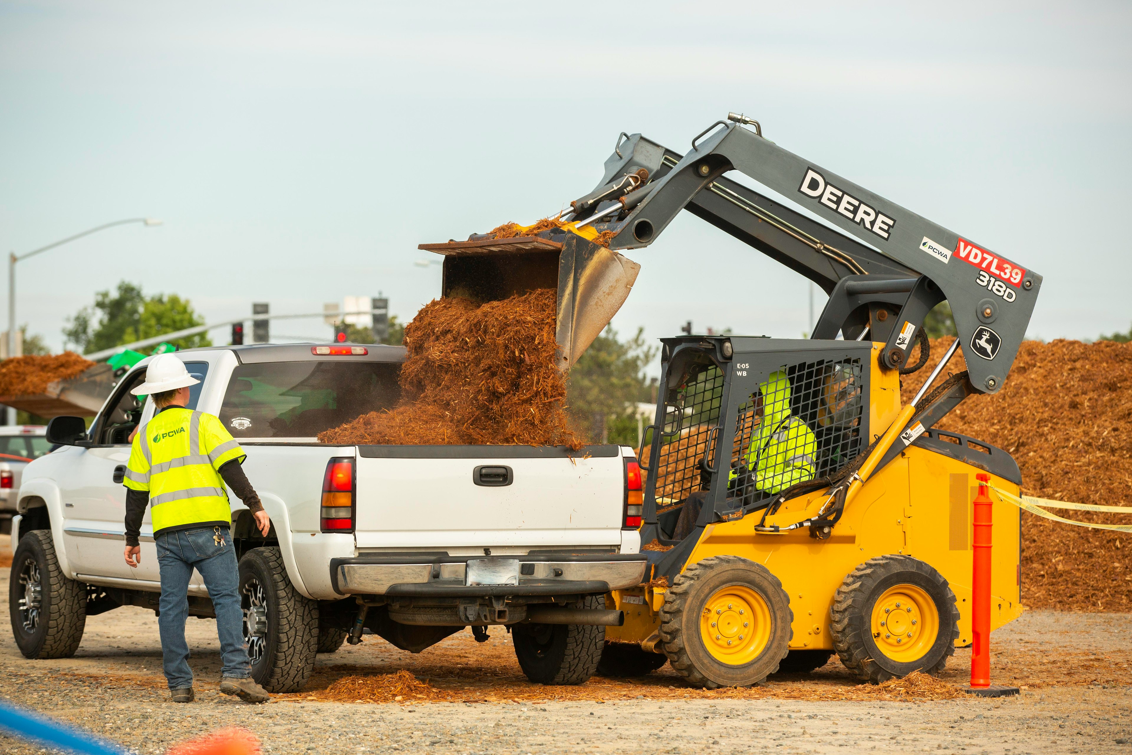 Tractor loading mulch into the bed of a pickup truck
